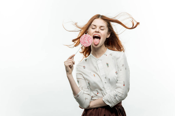 woman in white shirt with lollipop in hands charm of sweets - Foto, afbeelding