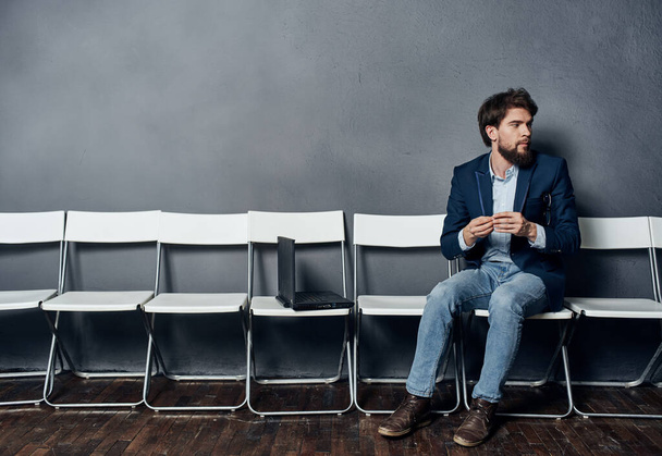 Hombre de negocios en un traje se sienta en una silla delante de un estilo de vida de trabajo portátil - Foto, Imagen