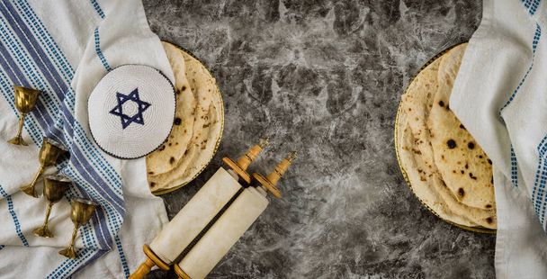 Orthodox Jewish family symbols with cup wine kosher matzah, traditional jewish passover holiday on Holy Scrolls torah - Photo, Image