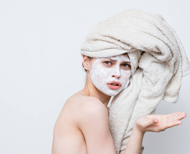 mujer divertida con toalla en la cabeza desnuda hombros máscara blanca en la cara - Foto, Imagen