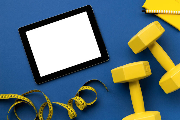 古典的な青の背景に黄色のスポーツ機器とフラットレイトップビュータブレット - 写真・画像