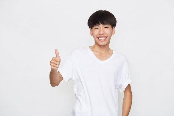 Asian young man wearing a T-shirt going thumb up on white background. - Photo, Image