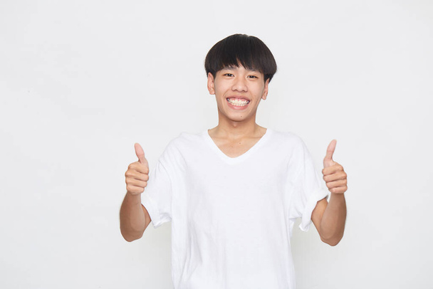 Asiático joven hombre usando un T-shirt ir pulgar arriba en blanco fondo. - Foto, imagen