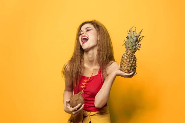 vrouw met ananas en kokosnoot cocktail exotische vruchten zomer levensstijl gele achtergrond - Foto, afbeelding