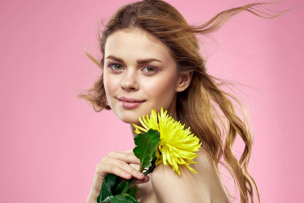 Προσωπογραφία γυναίκας με κίτρινα λουλούδια σε ροζ φόντο Μακιγιάζ στο πρόσωπο - Φωτογραφία, εικόνα