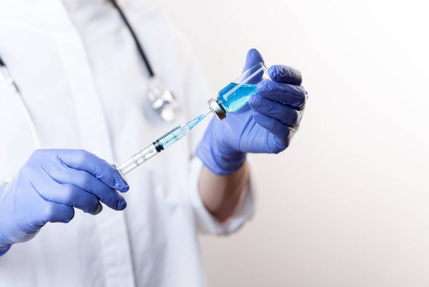 Medico in guanti che riempie la siringa dal flacone con vaccino, medicinale - Foto, immagini