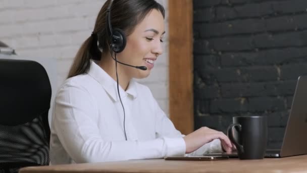 Χαμογελαστή γυναίκα τηλεφωνητή κέντρο, πράκτορας υποστήριξης πελατών φοράει ακουστικά συμβουλεύει τον πελάτη σε απευθείας σύνδεση δακτυλογράφηση στο laptop, να μιλήσει στο διαδίκτυο συνομιλία υπολογιστή, τηλεφωνήτρια γραμμή βοήθειας γραμματέας κάνουν τηλεδιάσκεψη κλήση βίντεο - Πλάνα, βίντεο