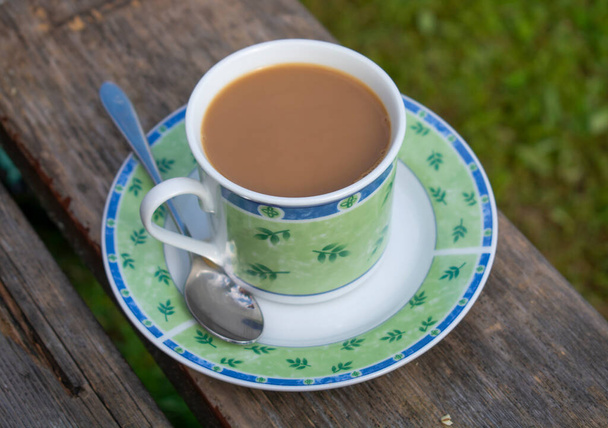 Vintage porcelain cup of hot coffee on a  saucer on old wooden table . - Photo, Image
