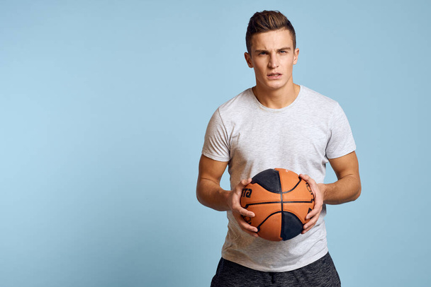 Sportovní muž hraje míč cvičení životní styl studio modré pozadí - Fotografie, Obrázek