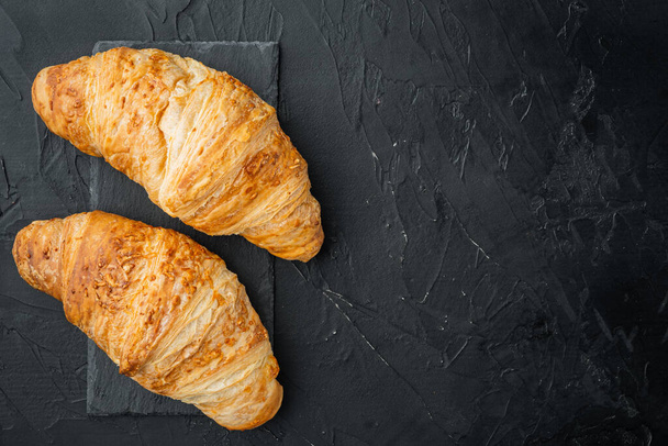Fresh homemade baked golden brown croissant set, on black stone background, top view flat lay, with copy space for text - Photo, Image