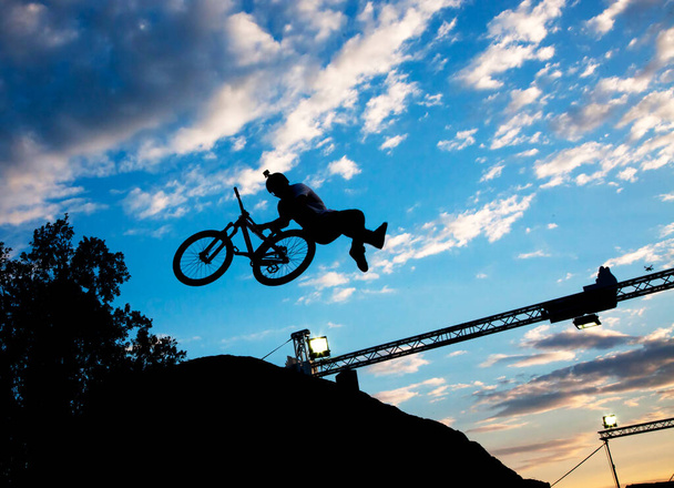 Силуэт человека, прыгающего с велосипеда на закатное небо - Фото, изображение