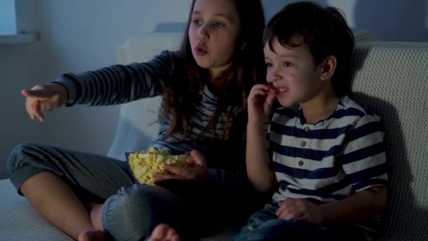 4k. petit caucasien fille et garçon regarder la télévision et manger pop-corn - Séquence, vidéo