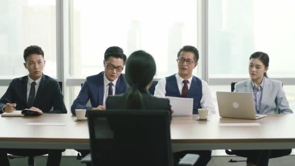 Rückansicht einer jungen asiatischen Geschäftsfrau, die von einer Gruppe von Personalverantwortlichen im Konferenzraum eines modernen Unternehmens interviewt wird - Filmmaterial, Video
