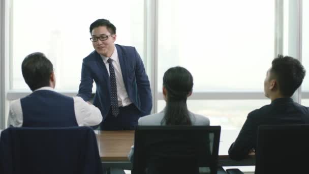 fiatal ázsiai üzletember munka kérelmező kezet rázva és üdvözölve egy csoport humán erőforrás vezetők konferenciateremben a modern vállalat - Felvétel, videó