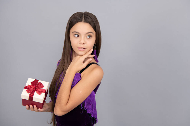Nettes Mädchen Kind halten Geburtstagsgeschenk Box mit roter Schleife Schleife grau Hintergrund Kopierraum, einkaufen. - Foto, Bild