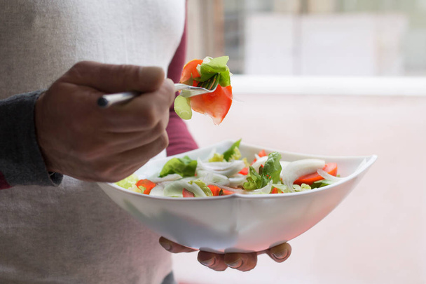man eating salad bowl with tomato and lettuce, diet and food concept - Photo, Image