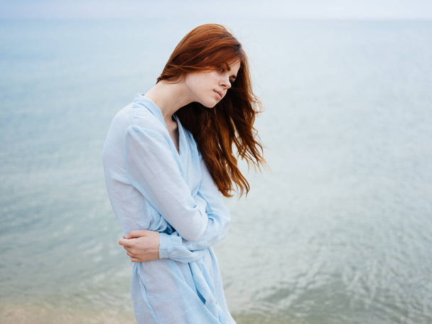 Woman on the beach near the ocean in a blue dress model red hair - Fotografie, Obrázek
