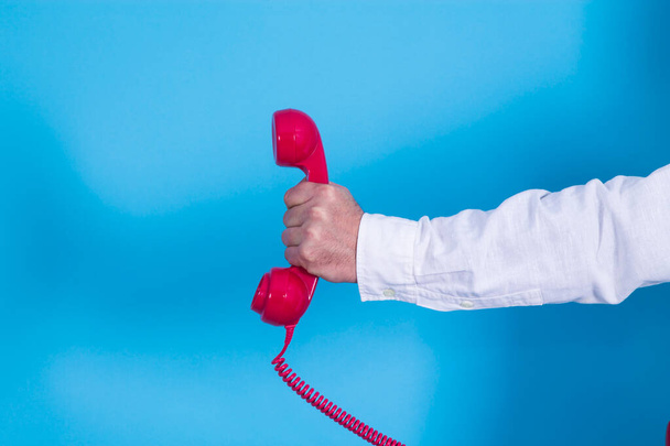 hand holding red phone in blue background - Photo, Image