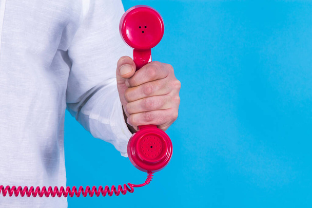 hand holding red phone in blue background - Фото, изображение