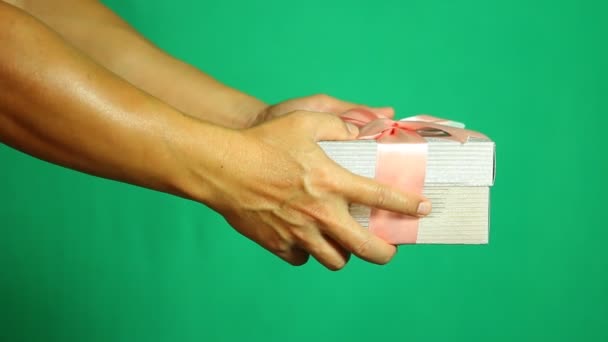 Ο άνθρωπος δίνει κουτί δώρου σε κάποιον με πράσινο φόντο, γυρίσματα στο στούντιο - Πλάνα, βίντεο