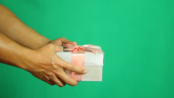 Man geven geschenk doos aan iemand met een groene achtergrond, schieten in de studio - Video