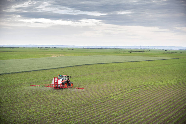 Тракторный аэрозоль удобряет поле инсектицидом гербицидов химикатами в сельском хозяйстве  - Фото, изображение