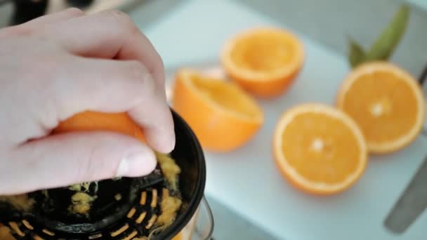 человек сжимает свежие фрукты апельсина на соковыжималке. Готовим здоровый завтрак из натурального ингредиента. Органические витаминные напитки - Кадры, видео