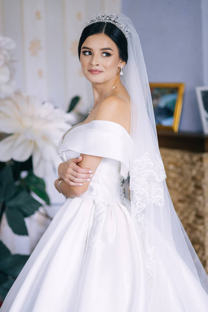 Élégante mariée dans un portrait d'une robe de mariée dans un hôtel, maquillage, et avec un voile sur la tête - Photo, image