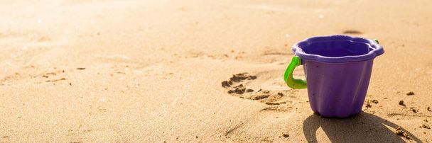 seau à jouets en plastique sur le sable par une journée ensoleillée. Bannière - Photo, image