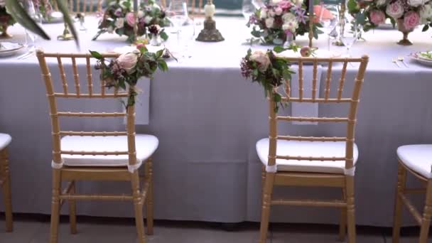 Krzesła przy stole na bankiecie weselnym, ozdobione kwiatami i świecznikami z płonącymi świecami na molo nad morzem - Materiał filmowy, wideo