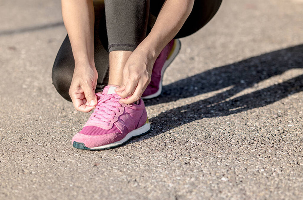 jeune femme est assis attachant chaussures de course avant de courir dans le parc. - Photo, image