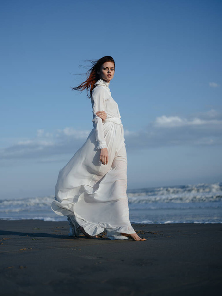 Жінка в білій сукні біля океану босоніж портрет в повному зростанні
 - Фото, зображення