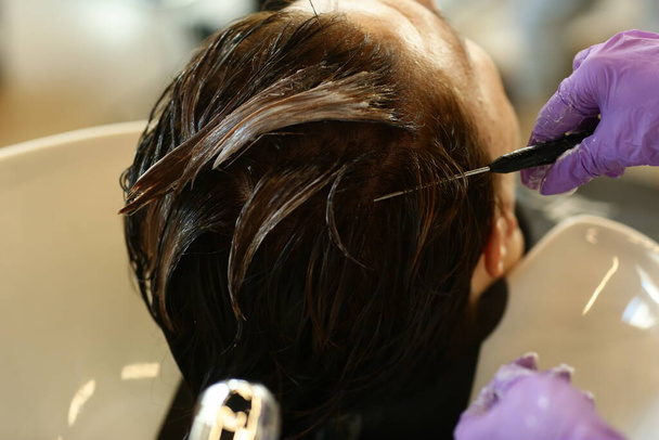 mão cabeleireiro com tintura de cabelo fazendo corte de cabelo e coloração de cabelo no cliente de perto foto - Foto, Imagem