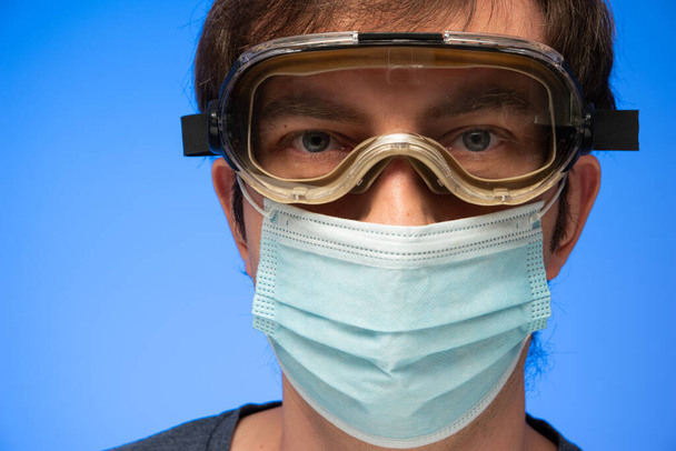 Caucasian male with protection goggles and face mask looking at the camera close up studio shot. - Photo, Image