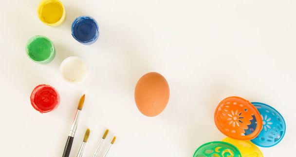 Пасхальне яйце, фарби, пензлі та трафарети для малювання на білому тлі. Підготовка до Великодня. Тло для дизайну. Місце для тексту
 - Фото, зображення
