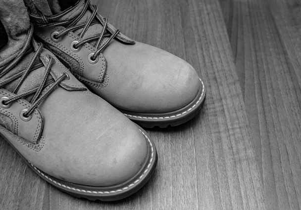 BCzarno-białe zbliżenie pary butów roboczych kolor brązowy na drewnianej podłodze - Zdjęcie, obraz