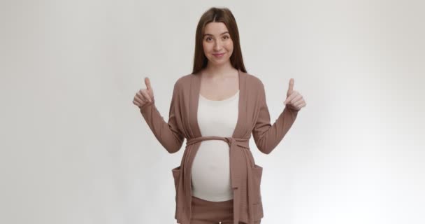 Pozitív fiatal terhes nő mutat a nagy has, mosolygós kamera, fehér stúdió háttér - Felvétel, videó