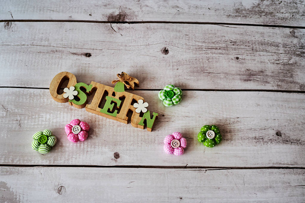 Signo de madera con un conejo de Pascua con flores como decoración. El texto es alemán para Pascua. - Foto, imagen