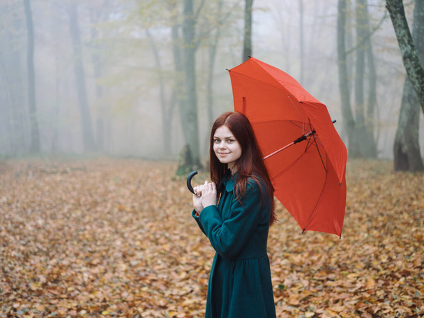 Pretty woman red umbrella walk in autumn in the forest with fog yellow leaves - Фото, зображення