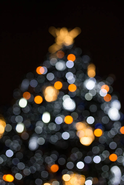 Siluetti sumea joulukuusi valaistu ja koristeltu kultainen keiju valot pimeässä yössä luoda kaunis bokeh vaikutus hehkuva piireissä - Valokuva, kuva