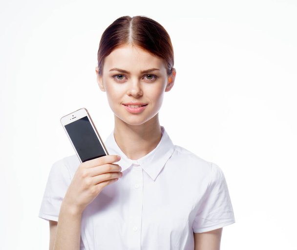 όμορφη γυναίκα σε λευκό πουκάμισο γραμματέας με τηλέφωνο στα χέρια επικοινωνίας τεχνολογίας - Φωτογραφία, εικόνα