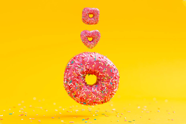 Três donuts de diferentes formas e tamanhos, com cobertura rosa. Fundo amarelo. Espaço de cópia. - Foto, Imagem