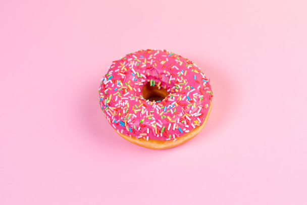 Round doughnut with pink icing close up. Pink background. Copy space. Flat lay. - Photo, Image