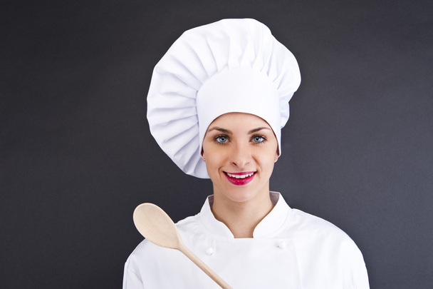 Chef in uniform holding a kitchen knife. Isolated on dark backgr - Foto, imagen