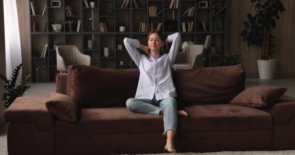 Young happy 35s caucasian woman relaxing on comfortable couch. - Imágenes, Vídeo