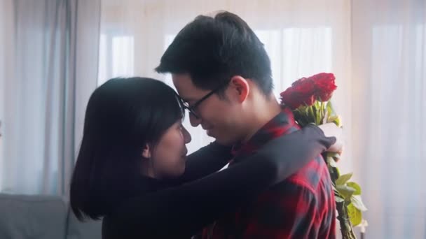 Nuori aasialainen mies yllättää tyttöystävänsä kanssa kimppu punaisia ruusuja - Materiaali, video