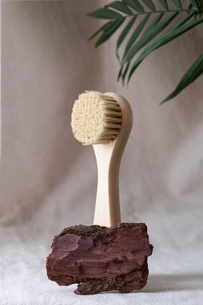 Facial massage brush with natural bristles on a linen background with bark palm leaf. . eco friendly cosmetics concept.. - Photo, Image