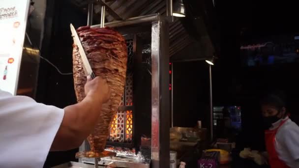 Manos masculinas rebanando un baúl pastor mexicano tradicional fuera de un restaurante - Imágenes, Vídeo
