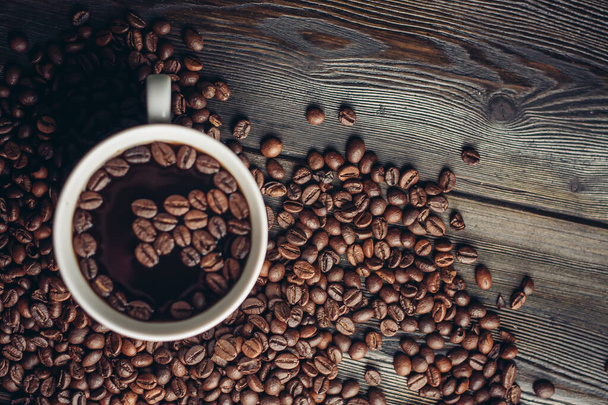 чашка з ароматним напоєм і кавовими зернами на дерев'яному фоні вид зверху
 - Фото, зображення