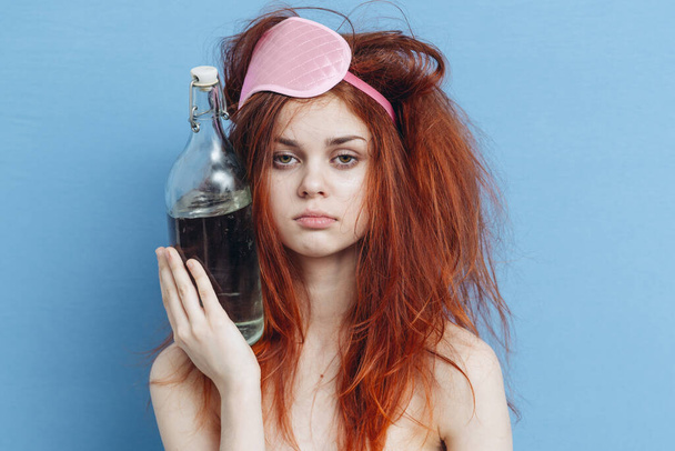 drunk woman with disheveled hair mask red bottle of alcohol - Photo, Image
